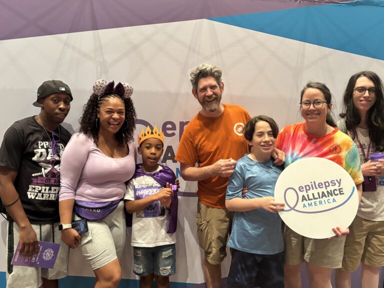 Families attending Epilepsy Awareness Day at Walt Disney World pose together holding an Epilepsy Alliance America sign.