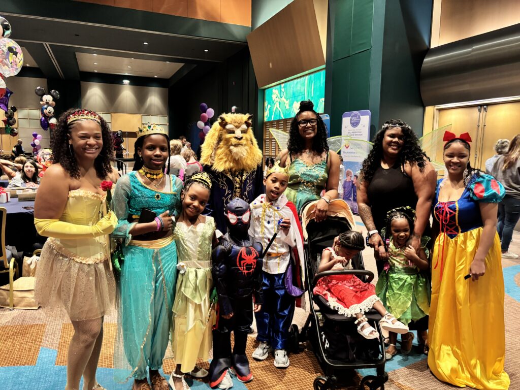 Families attending Epilepsy Awareness Day at Walt Disney World pose for a group photo dressed as and alongside princesses.