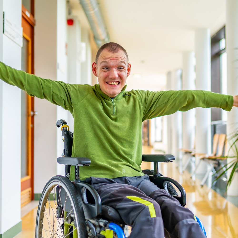 A smiling man with a disability using a wheelchair.
