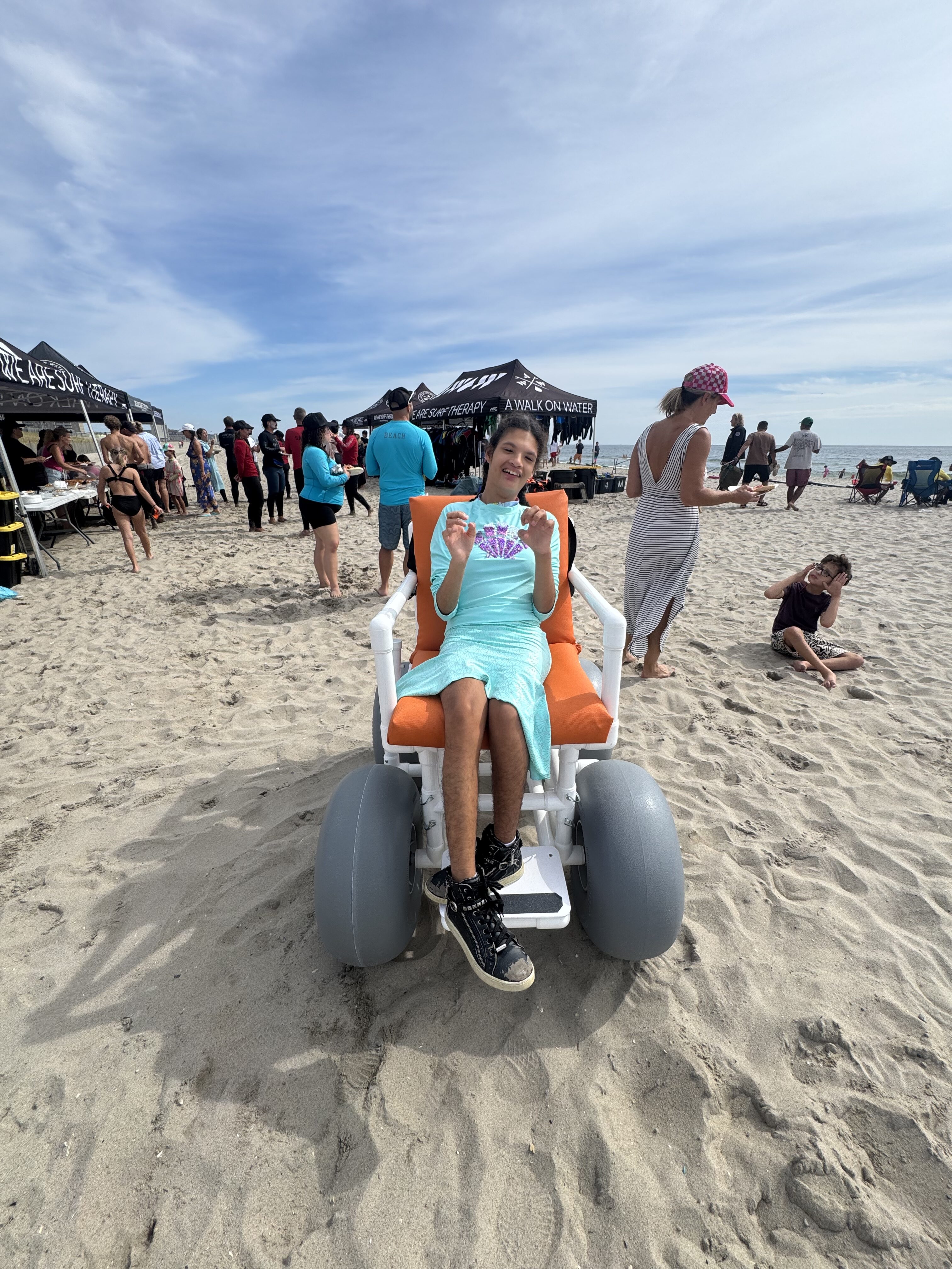 Arizona in an accessible beach wheelchair provided through Family Resource Network's AT/HVM program