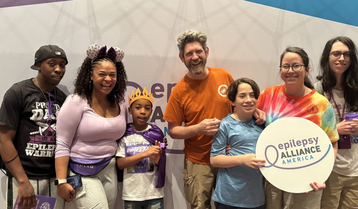 Families attending Epilepsy Awareness Day at Walt Disney World pose together holding an Epilepsy Alliance America sign.